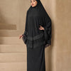 Eine Frau trägt ein elegantes schwarzes, mehrlagiges Spitzen-Khimar-Abaya-Set.