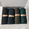 Eine Box mit vier zerknitterten Baumwoll-Hijab-Schals in Schwarz, Marineblau, Olivgrün und Türkis.
