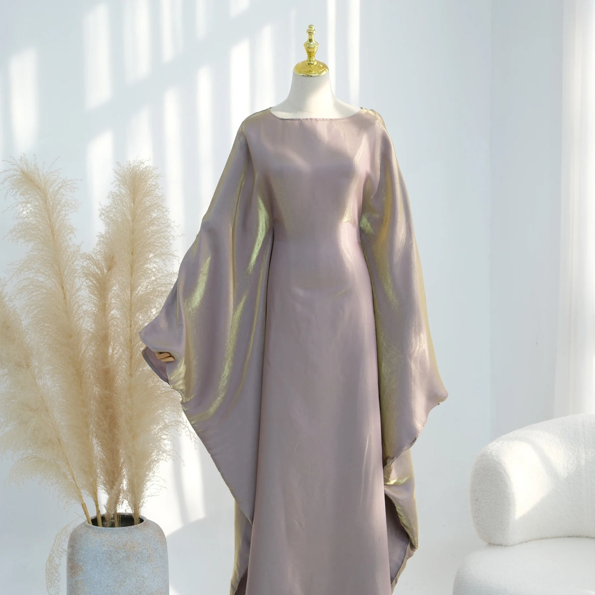 Langes mauvefarbenes Kaftankleid mit durchscheinenden goldenen Akzenten auf einem Mannequin.