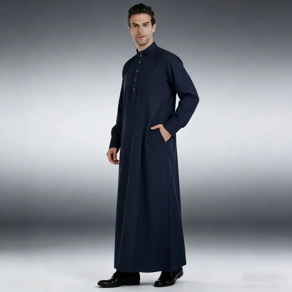 Männliches Model trägt einen dunkelblauen Islam Jalabiya Thobe Kaftan vor grauem Hintergrund.