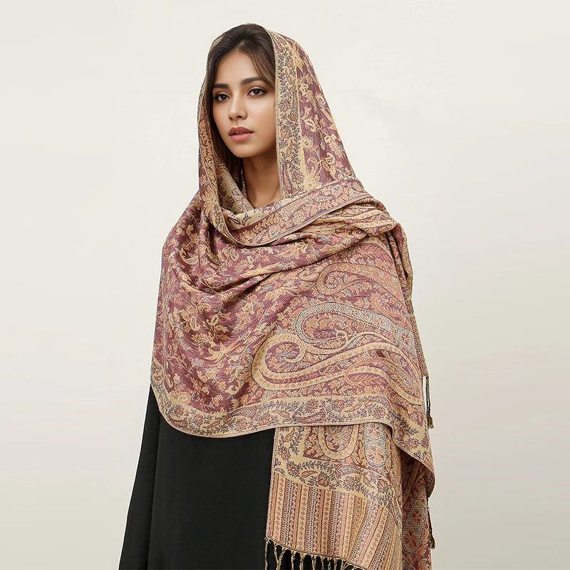 Una mujer modela un pañuelo pashmina de lujo en tonos malva y beige sobre una prenda negra.