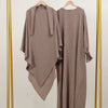 A beige elegant two-piece abaya and khimar set displayed on a gold hanger against a light background.