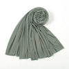 Un foulard hijab en jersey de coton vert sauge, roulé et drapé, montrant sa texture.