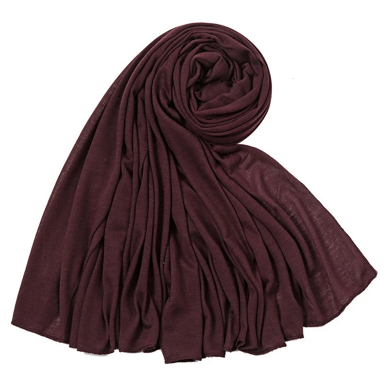 Ein tiefmaroniger, einfacher Baumwoll-Jersey-Schal für Damen, gerollt und drapiert.