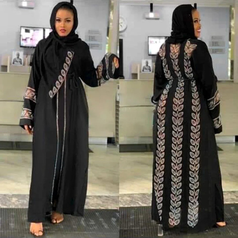 Una mujer vistiendo una elegante abaya negra con bordados intrincados y un hiyab negro.