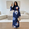 Eine Frau modelliert ein dunkelblaues Abaya-Kleid mit Blumenstickerei in einem hellen Raum.