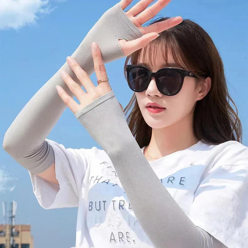 A woman wearing light gray cooling UV protection arm sleeves against a blue sky background.