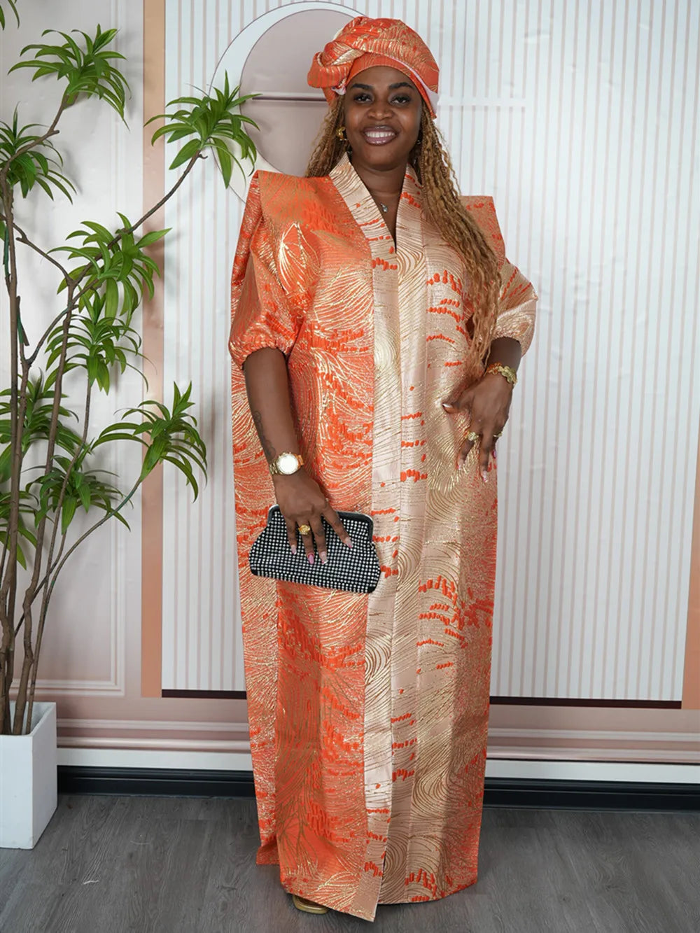 A woman wearing an orange satin kaftan abaya with gold embroidery and matching jewelry.