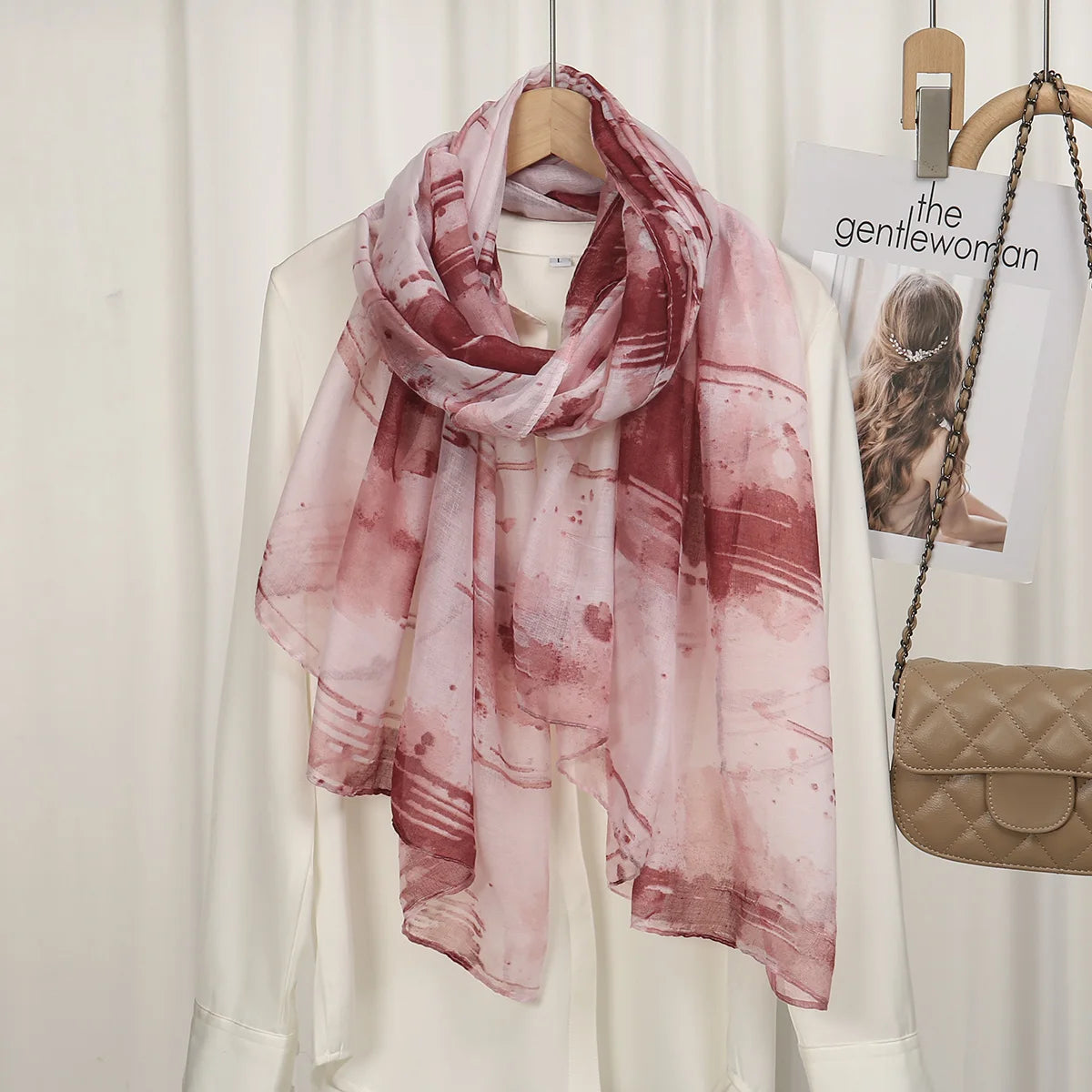 Pañuelo de chifón de algodón estampado rosa y granate drapeado sobre una prenda blanca.