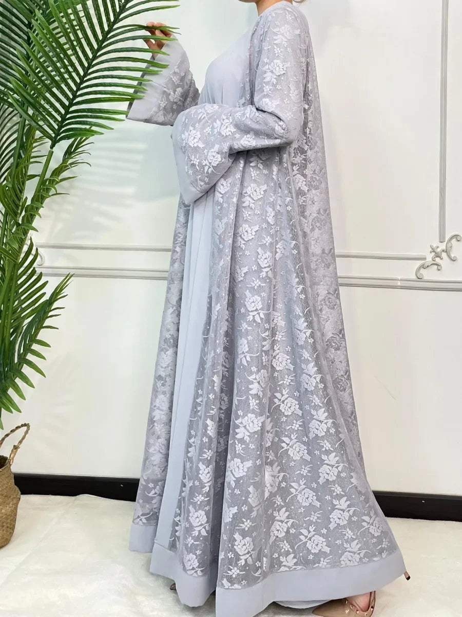 Une longue abaya en dentelle gris clair pour femmes à manches longues et silhouette fluide.