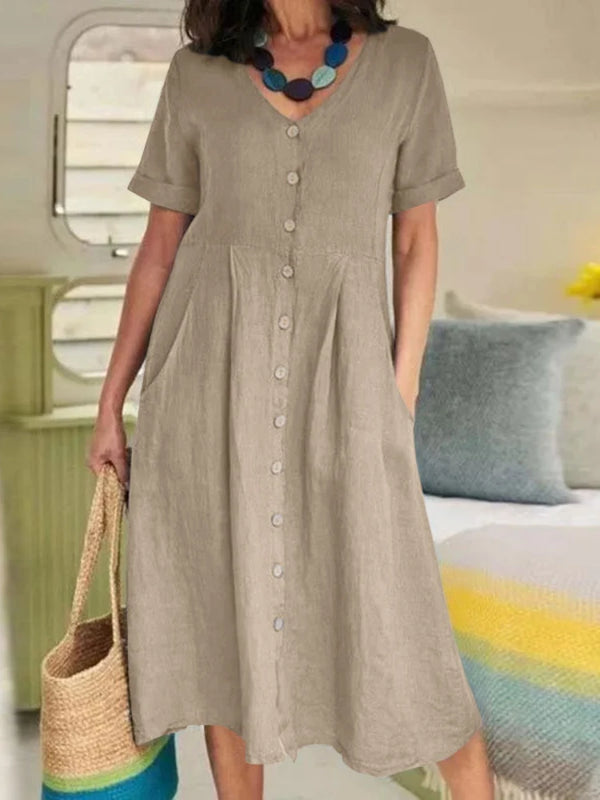 A woman models an elegant, loose-fitting, short-sleeved cotton and hemp V-neck dress in a natural beige color.