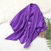 A purple silk satin hijab scarf draped over a white fluffy surface.