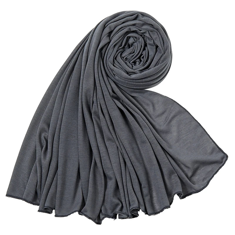 Dunkelgraves Baumwoll-Jersey-Hijab-Schal, fest gerollt und drapiert, zeigt seine weiche Textur.