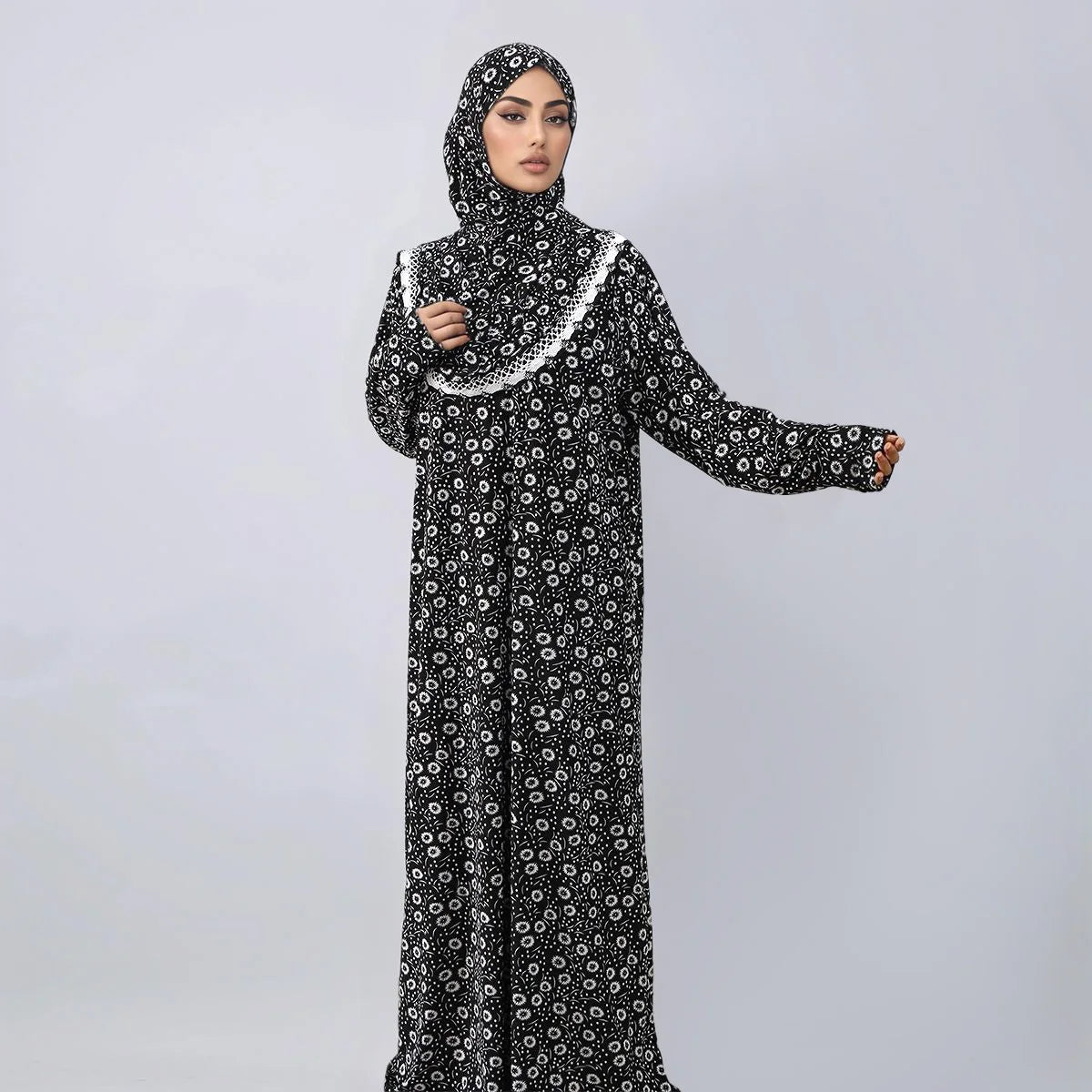 A woman wearing an elegant black and white patterned Muslim hijab dress for prayer and daily wear.