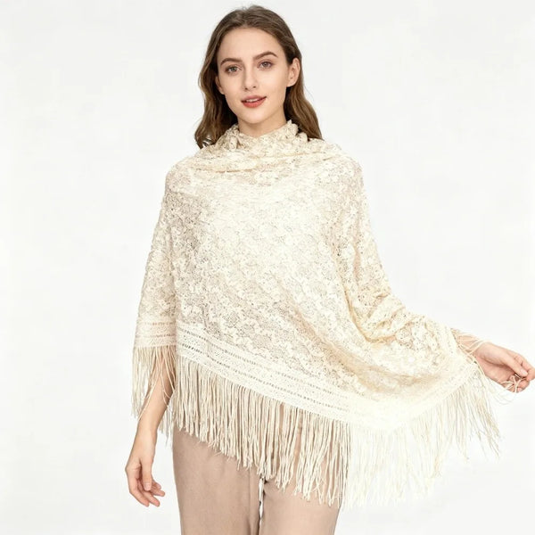A woman models an elegant cream knitted lace shawl with fringe details.