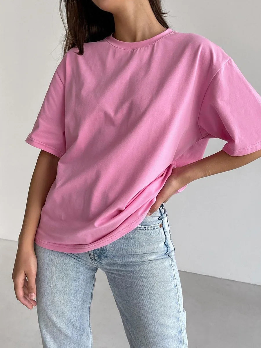 Modelo vistiendo una camiseta básica de algodón rosa oversize y jeans de lavado claro.