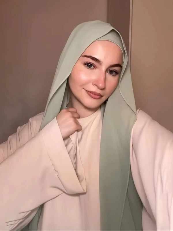 A woman wearing a light green chiffon matching inner scarf set with a pale pink top.