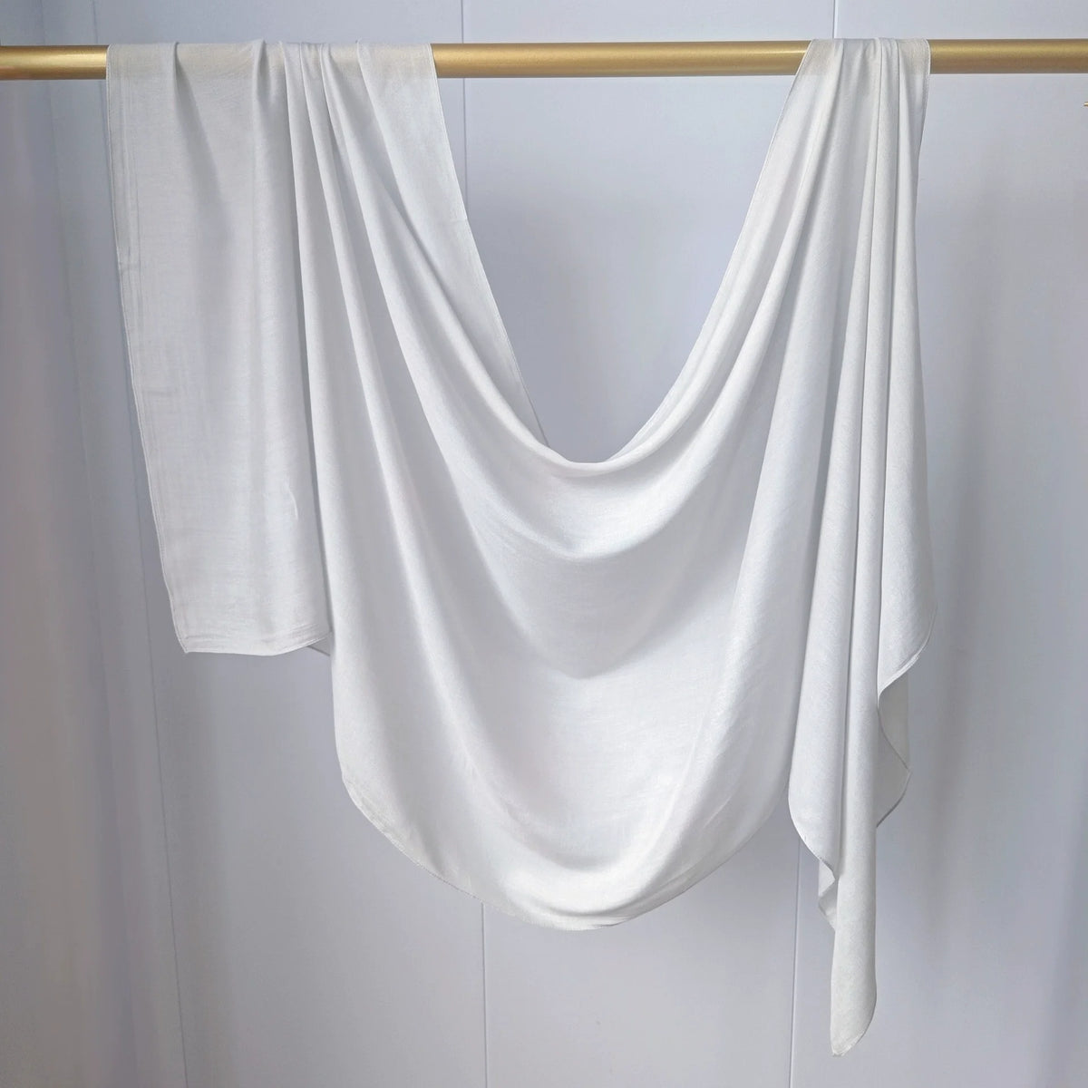 Foulard hijab de couleur unie blanche drapé sur un cintre en bois.