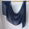 Foulard hijab uni bleu foncé drapé sur un cintre en bois.