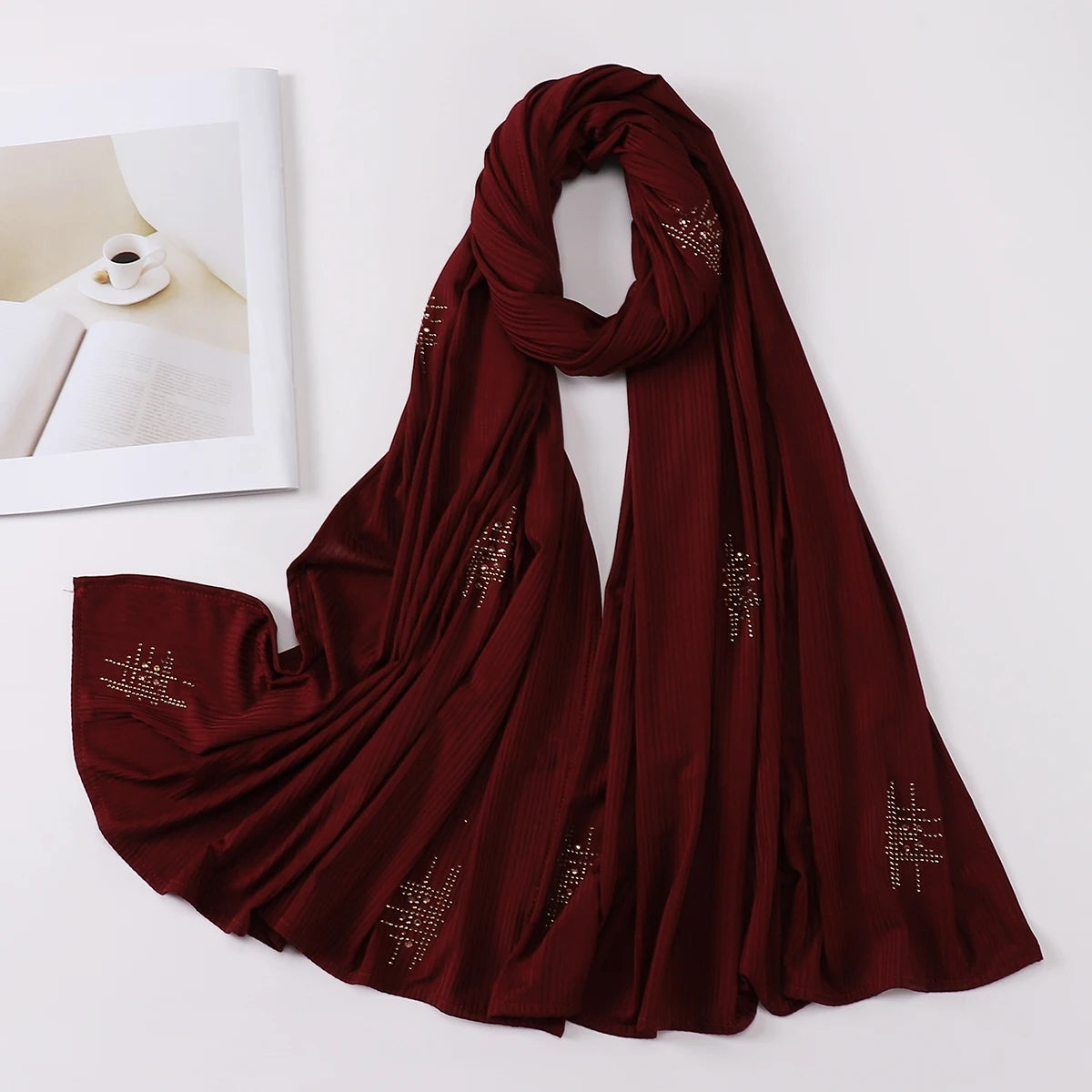 Tiefmarooner gerillter Jersey-Hijab-Schal elegant über einer weißen Fläche drapiert.