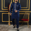 Un homme portant un costume de mariage musulman traditionnel africain bleu marine avec broderies et pantalons sombres.