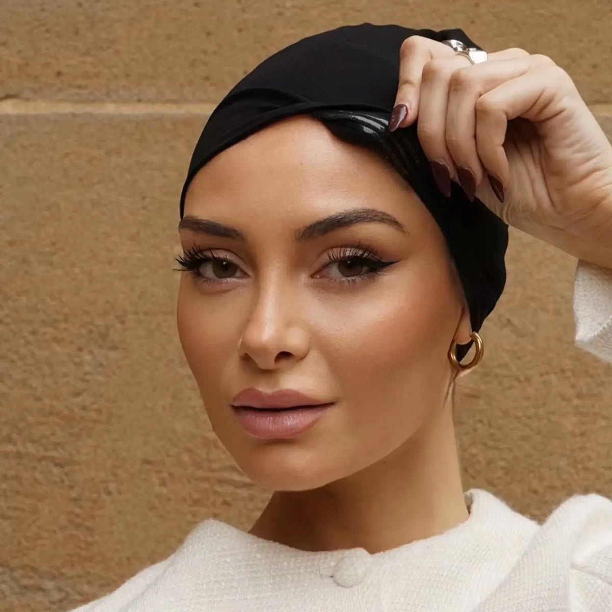 Une femme portant un foulard turban élastique noir, regardant directement l'appareil photo.