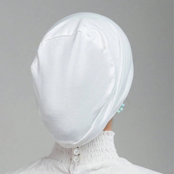 White stretch jersey inner hijab cap worn by a woman with a high neck collar.