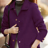 Une femme portant un manteau en laine violet sur un col roulé gris et un pantalon clair.