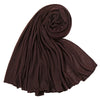 Un foulard hijab en jersey de coton brun foncé, roulé et drapé, montrant sa texture douce.