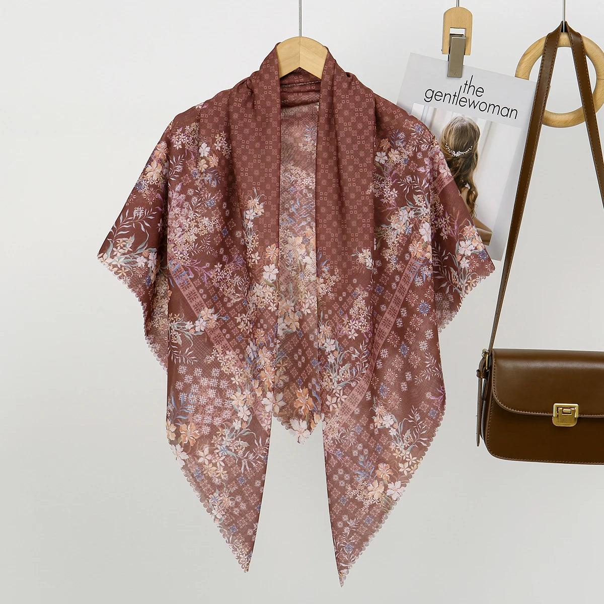 Mauve blumiges quadratisches Hijab-Tuch, auf einem Holzstab aufgehängt.