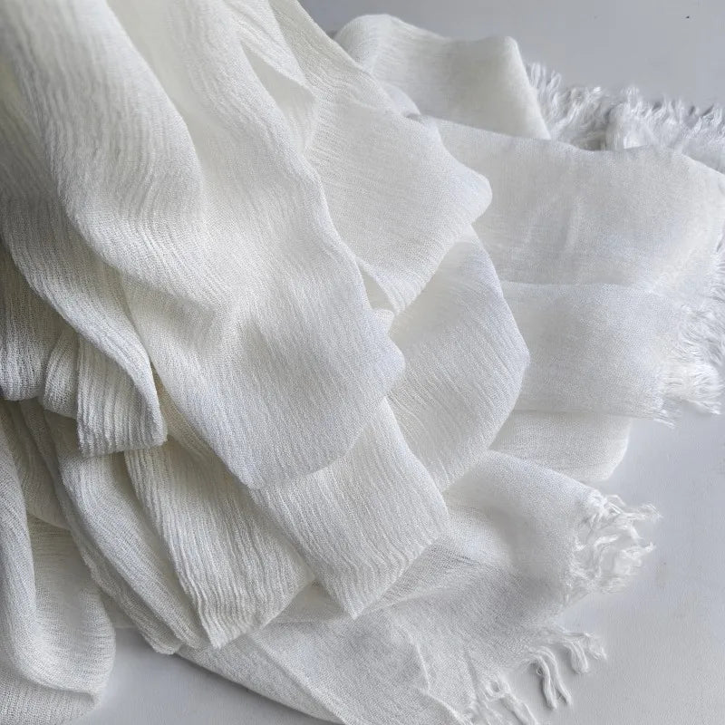 Foulard hijab en coton viscose blanc doux avec pompons, montré en tissu drapé.