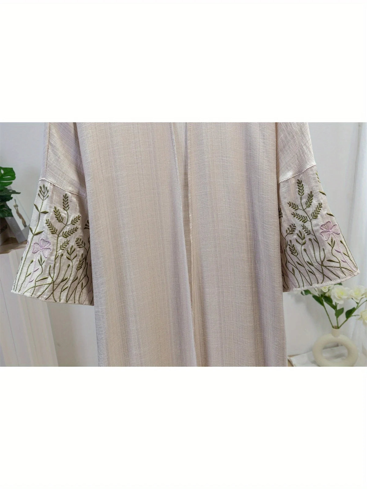 Helle beige Kaftan-Abaya mit zarten grünen und rosa Stickereien an den Ärmeln.
