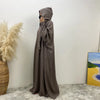 Une longue abaya gris foncé avec capuche et manches batwing, exposée contre un mur blanc.