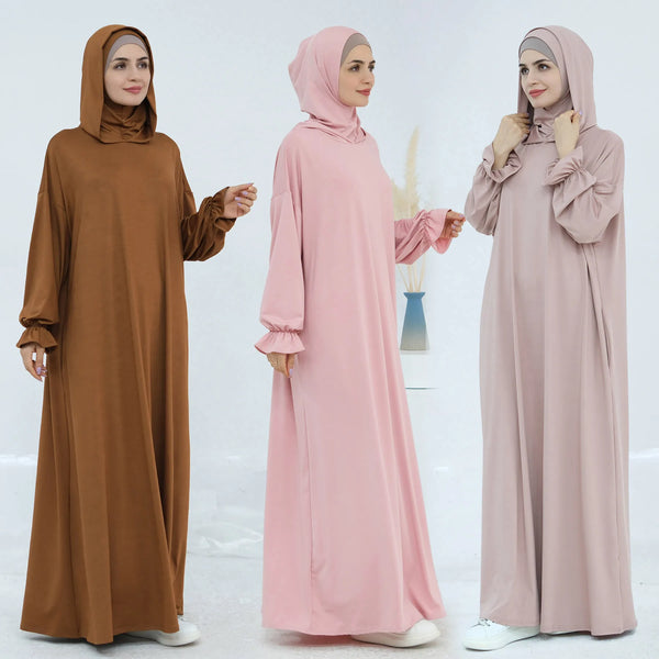 Three women wearing flowy loose fit abaya dresses in brown, pink, and mauve tones.