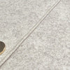 Gros plan sur un tissu en laine gris clair avec une couture visible et deux boutons ronds dorés.