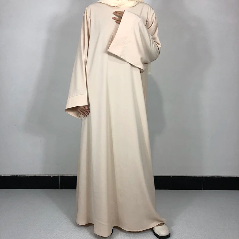 Robe Nida Abaya beige unie présentée sur un mannequin.
