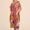 Una mujer modela un vestido caftán playero amarillo con estampado floral rosa y morado vibrante.