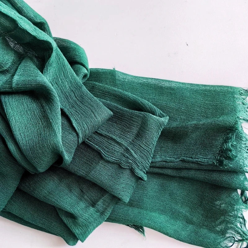 Une pile de foulards de hijab en viscose coton vert sarcelle avec pompons.
