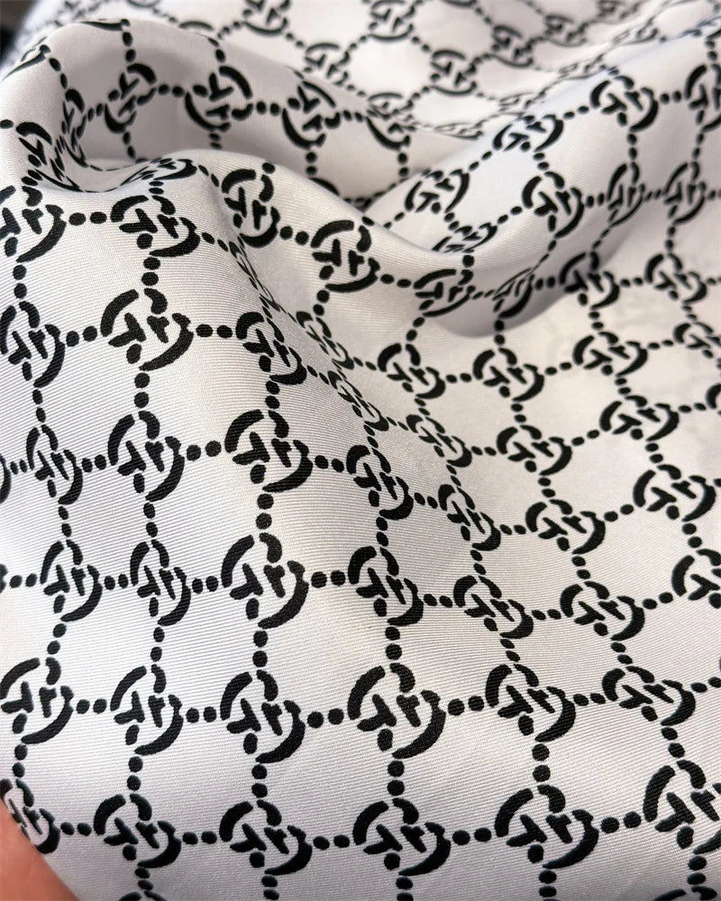 Nahaufnahme eines weißen Seidenschals mit schwarzem geometrischem Kettmuster
