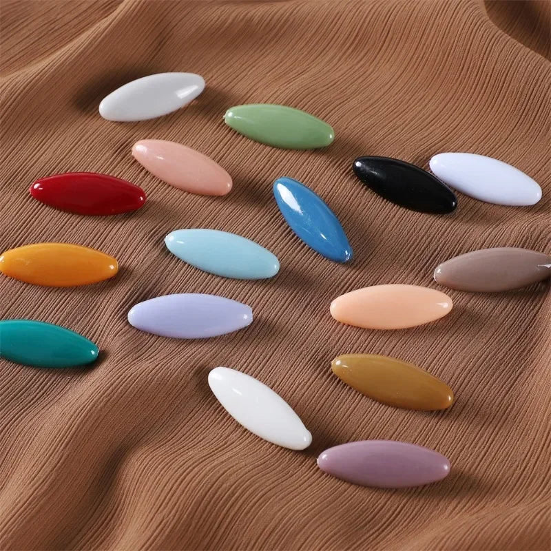 Eine Sammlung farbenfroher Sicherheits-Hijab-Pins und Broschen in verschiedenen Pastelltönen auf braunem Stoff.