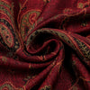 Nahaufnahme eines tiefroten Paisley-Viskose-Hijab-Stoffes mit goldenen Akzenten, fest gerollt.