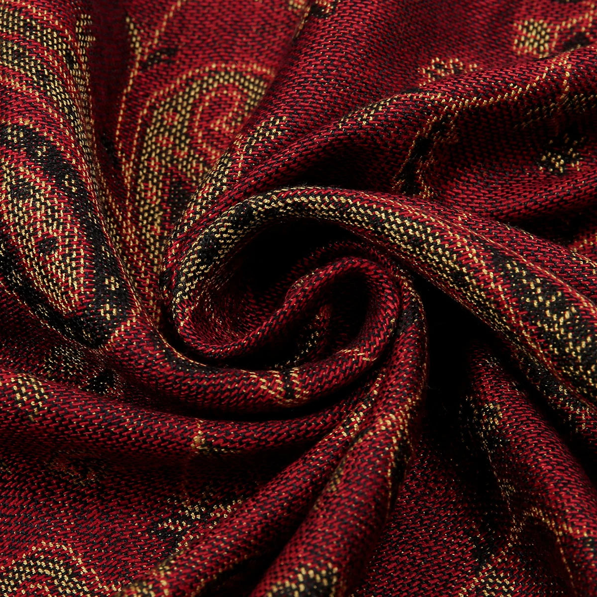 Nahaufnahme eines tiefroten Paisley-Viskose-Hijab-Stoffes mit goldenen Akzenten, fest gerollt.