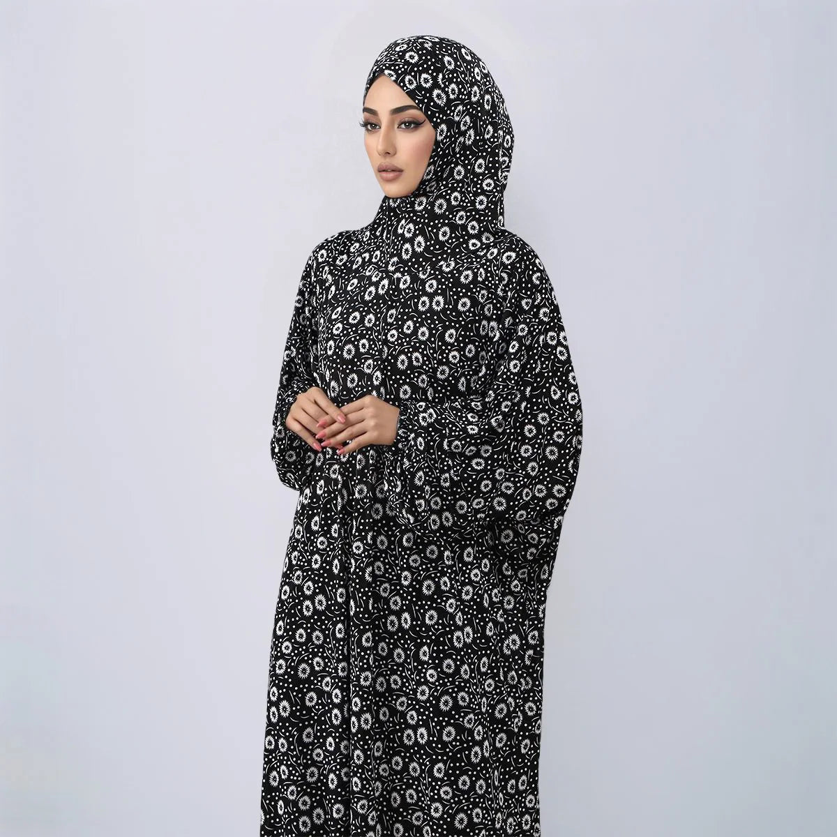 Una mujer vistiendo una abaya de lino floral negra con capucha y turbante.