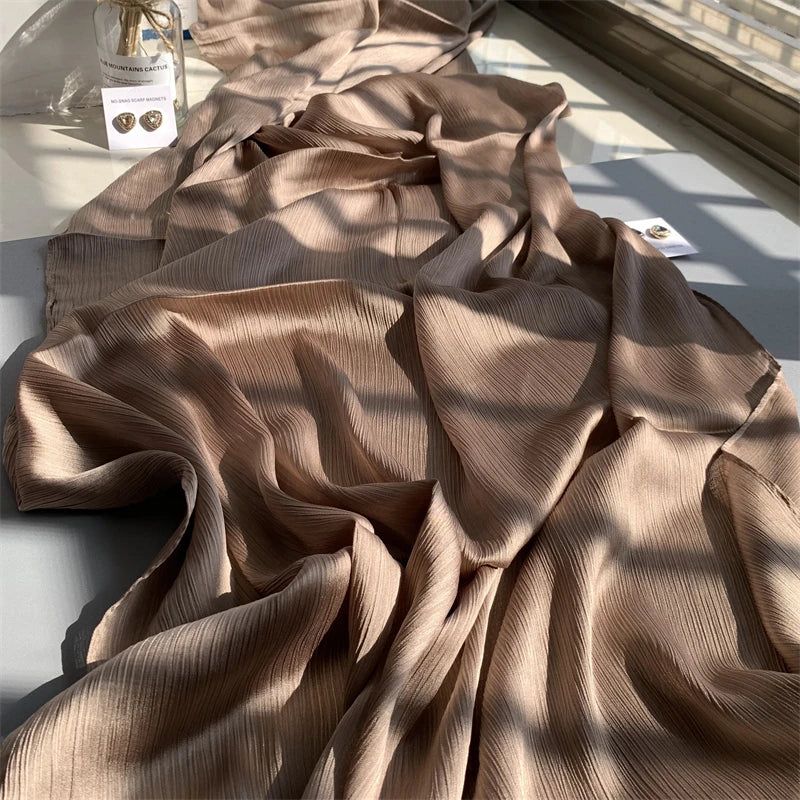 Beige, gerüschter Satin-Chiffon-Hijabstoff in weichen Falten bei natürlichem Licht.