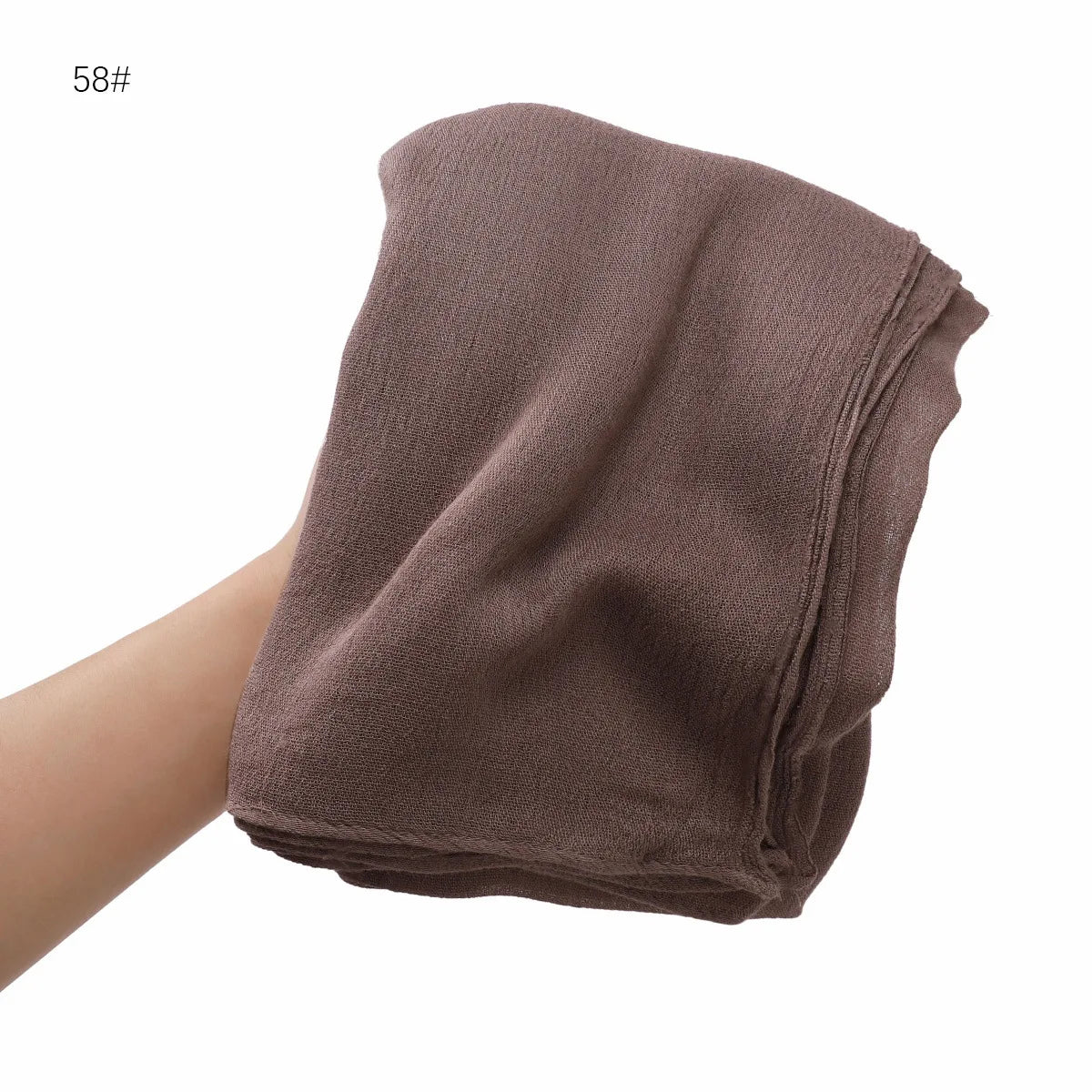 Gros plan d'un châle en crêpe de rayon marron tenu par une main.