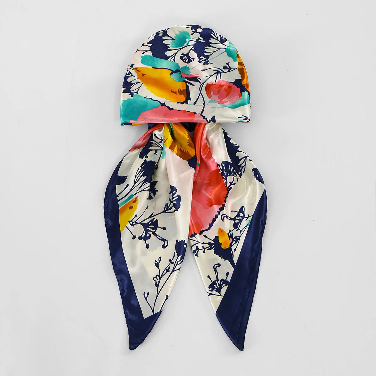 Pañuelo de turbante satinado colorido con estampados florales en tonos verde azulado, amarillo, rosa y azul marino.