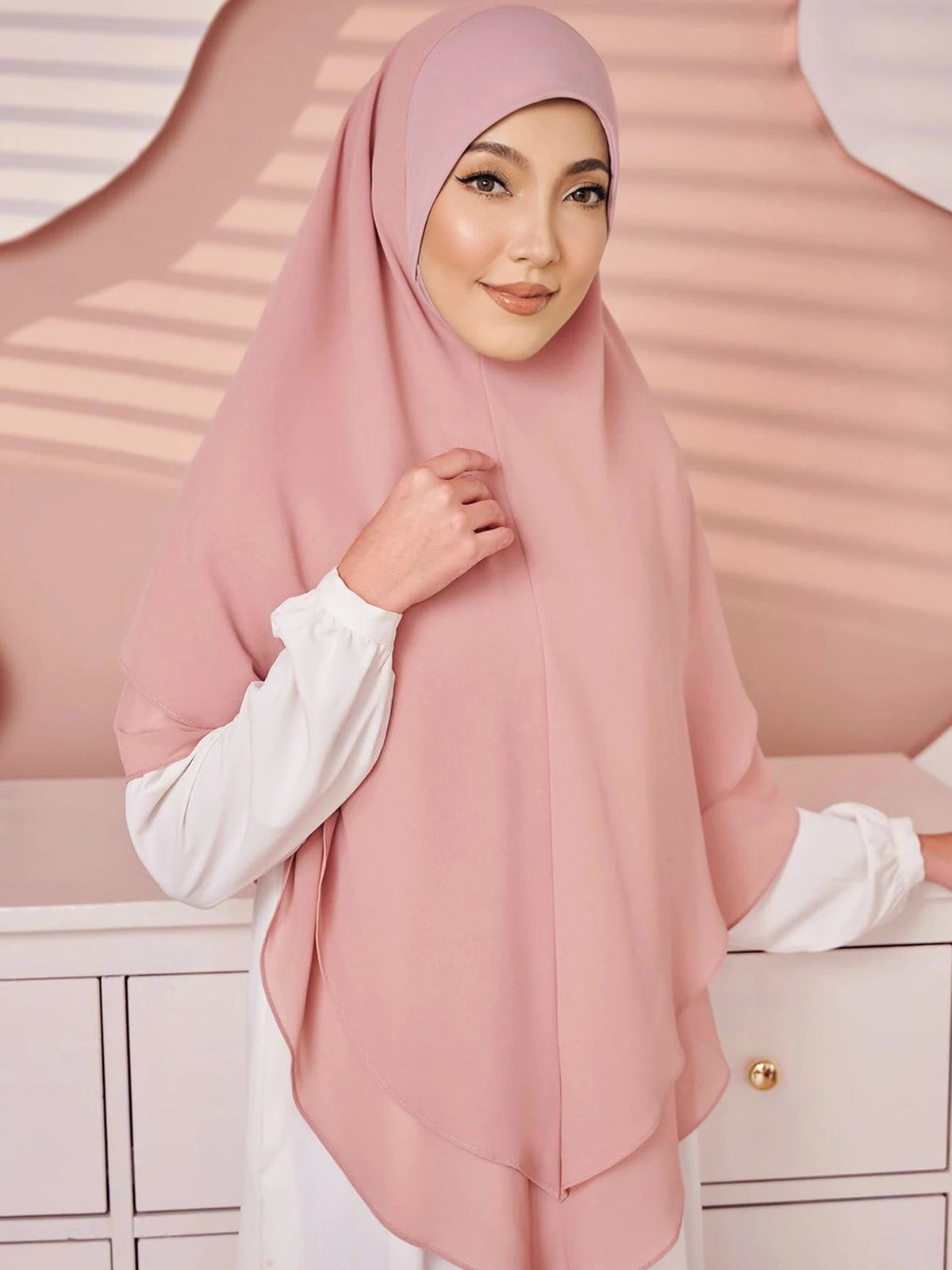 Eine Frau trägt einen rosa doppelschichtigen Chiffon-Instant-Hijab und ein weißes Hemd.