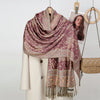 Chal de bordado paisley morado drapeado sobre una prenda blanca, exhibido con perchas de madera.