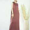 A woman models a flowing, mauve abaya dress against a white background.