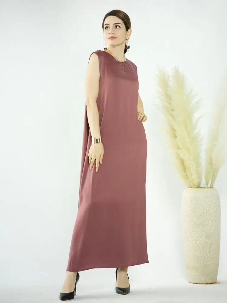 A woman models a flowing, mauve abaya dress against a white background.